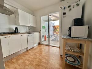 a kitchen with white cabinets and a microwave at Casita de Bolonia in Bolonia