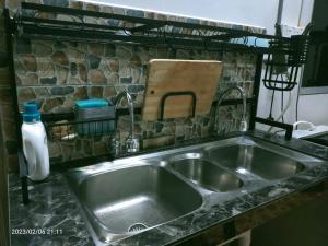 a stainless steel sink in a kitchen with a stone wall at Kuantan Homestay WiFi Viu PS4 BBQ by Zaryqa in Kuantan +135 photos