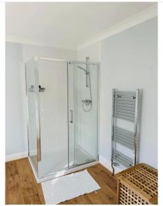 a glass shower stall in a room with a wooden floor at Romney Home in Maidstone