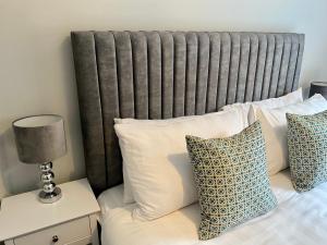 a bed with white pillows and a gray headboard at Luxury Riverside City Centre Apartment in York