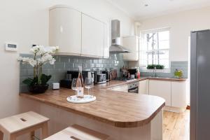 uma cozinha com armários brancos e um balcão de madeira em Kensington Nest Serviced House em Londres