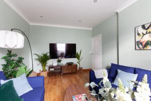 sala de estar con sofá azul y mesa en Kensington Nest Serviced House, en Londres