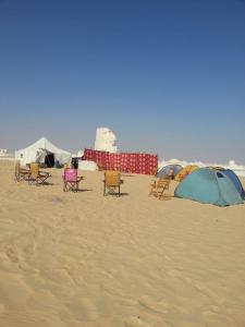 a group of chairs and tents on a beach at stars camp oasis in Bawiti