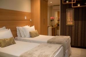 um quarto de hotel com duas camas com lençóis brancos em Hotel Cravo e Canela em Campos dos Goytacazes