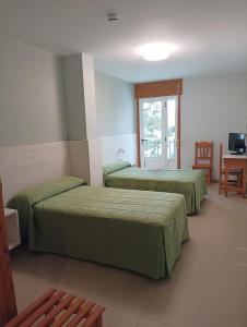 Habitación de hotel con 2 camas y mesa en Hotel Villa Jardín en Portomarin