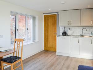 a kitchen with white cabinets and a table and a chair at Willow Tree Farm in Sutton on Sea