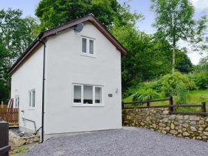 una casa blanca con una pared de piedra y una valla en Bryn Aled en Llanfachreth