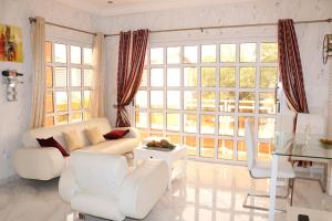 a living room with white furniture and large windows at Appartement Altona in Lomé
