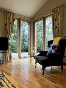 uma sala de estar com uma cadeira e janelas grandes em Ballyhoura Forest Home em Ballyorgan