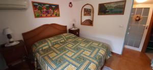 ein Schlafzimmer mit einem Bett mit einer Decke darauf in der Unterkunft Le Coin Vert in Fregene