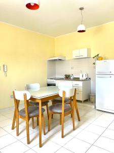 La cuisine est équipée d'une table, de chaises et d'un réfrigérateur blanc. dans l'établissement COMPLEJO ECHAGUE, à San Juan