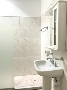 La salle de bains blanche est pourvue d'un lavabo et d'un miroir. dans l'établissement COMPLEJO ECHAGUE, à San Juan