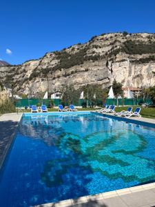 a swimming pool with chairs and a mountain in the background at Villa Franca in Nago-Torbole