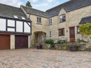 a brick house with a garage and a driveway at No 2, The Stables in Southam