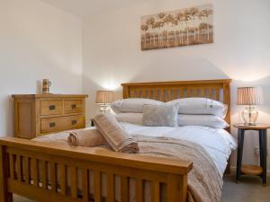 een slaapkamer met een groot houten bed met kussens bij No 2, The Stables in Southam