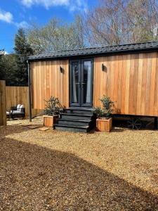 a wooden house with a black door and some plants at Canalside View Mini Lodge with private hot tub in Llangollen