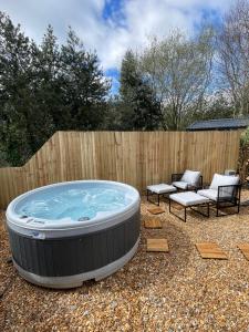 a hot tub in a yard with two chairs and a fence at Canalside View Mini Lodge with private hot tub in Llangollen