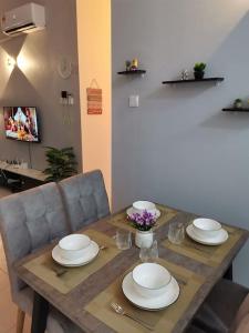 een houten tafel met borden en bloemen erop bij Casa Apartment @ Ipoh 【怡保民宿】 in Ipoh
