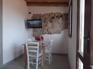 a table with white chairs and a tv on a wall at Casale Tano in Pachino