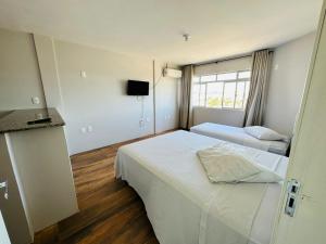 ein Hotelzimmer mit 2 Betten und einem TV in der Unterkunft Nacional Hotel Coral in Lages