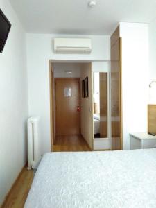 sypialnia z białym łóżkiem i korytarzem w obiekcie Hostal Nersan2 w Madrycie