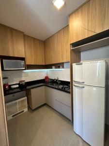 cocina con nevera blanca y armarios de madera en Flat em Brasília - Moderno e equipado en Brasilia