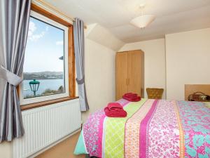 a bedroom with a bed and a large window at Waterside Cottage in Kyleakin