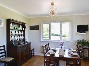 uma sala de jantar com uma mesa e um lustre em Glennydd em Bronant