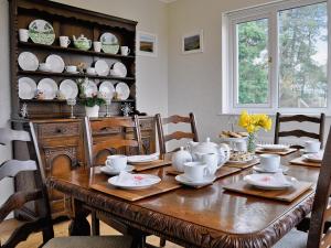 uma sala de jantar com uma mesa de madeira com pratos em Glennydd em Bronant