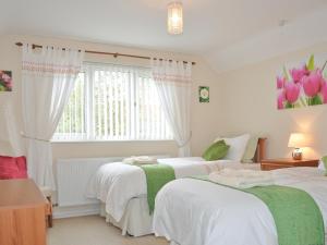a bedroom with two beds and a window with pink tulips at Glennydd in Bronant