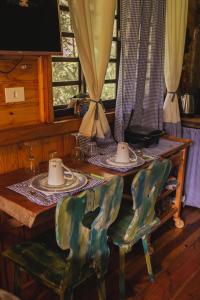 a wooden table with two plates and cups on it at Recanto de Encantos in Campos do Jordão +111 photos