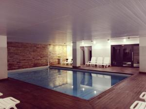 a swimming pool with white chairs and a brick wall at Golden Beach Resort & Spa in Punta del Este