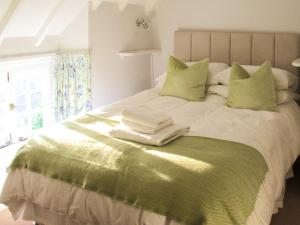 - un lit avec des draps et des oreillers verts et blancs dans l'établissement Cuckoo Nod Cottage, à Wool