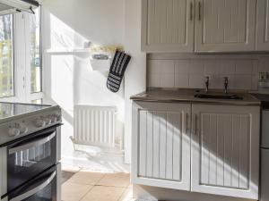 een keuken met witte kasten, een wastafel en een fornuis bij Hobbit House in Horncliffe