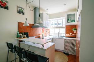 リスボンにあるAlameda Apartments & Roomsのキッチン(白いカウンター、黒い椅子付)