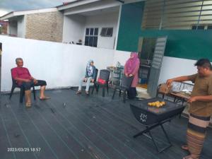 a group of people sitting on a deck with a grill at Kuantan Homestay Best Facility Wifi BBQ Viu in Kuantan