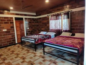 a bedroom with two beds and a brick wall at Green Hills Farm And Guest House in Masinagudi