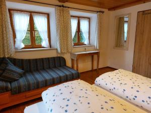 a living room with a couch and a bed and windows at Ferienwohnungen Haus Moser in Berchtesgaden