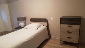 een slaapkamer met een bed en een dressoir met een lamp bij Maison de Romagers in Aumont-Aubrac