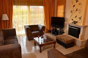 a living room with a couch and a table and a tv at Villa Gray in Ixia