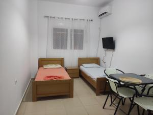 a room with two beds and a table and a television at IONIAN PEARL in Borsh