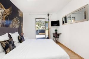 ein weißes Schlafzimmer mit einem großen Bett und einem Spiegel in der Unterkunft Studio au calme, avec terrasse et parking à Eze village in Èze