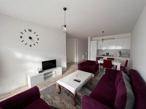 un soggiorno con mobili viola e un orologio sul muro di Cosy Apartment with a Great View a Pristina