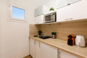 eine Küche mit weißen Schränken, einer Spüle und einer Mikrowelle in der Unterkunft Studio au calme, avec terrasse et parking à Eze village in Èze