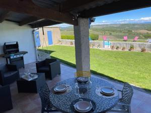 a patio with a table and chairs and a grill at La Ferme l'Etang in Vachères