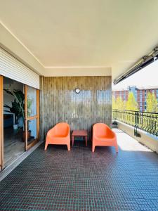 米蘭的住宿－Green Guest House，阳台上配有两把橙色椅子和一张桌子