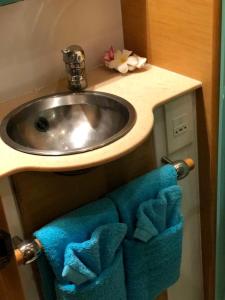 La salle de bains est pourvue d'un lavabo et de serviettes bleues. dans l'établissement Catamaran Apetahi, à Uturoa