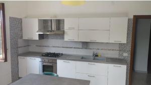 a kitchen with white cabinets and a sink and a stove at Appartamento Le Margherite in Procida
