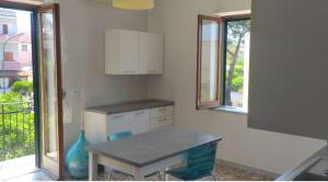 a kitchen with a table and two windows at Appartamento Le Margherite in Procida