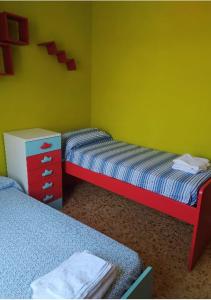 a room with two beds and a yellow wall at Appartamento Le Margherite in Procida +1 photo